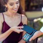 A happy woman paying with her smartphone on a card machine