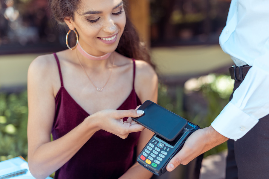 A happy woman paying with her smartphone on a card machine