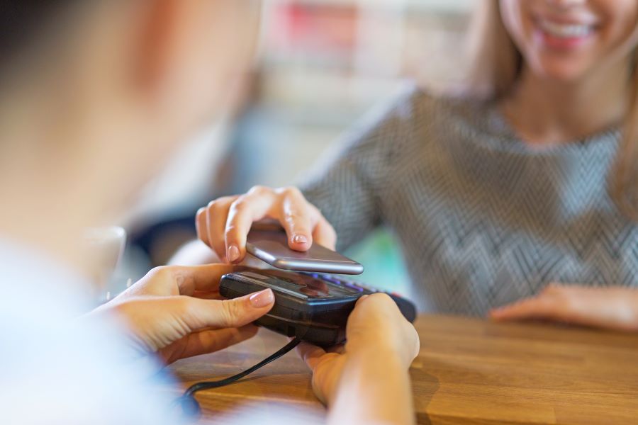 A woman pays with her smartphone on a Chip and PIN card machine.