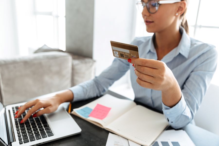 Businesswoman holding credit card and calculating card interchange fees.