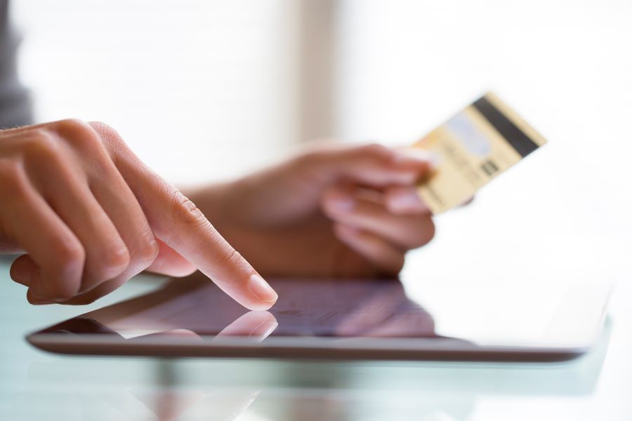 A woman enters her credit card PIN on a merchant tablet