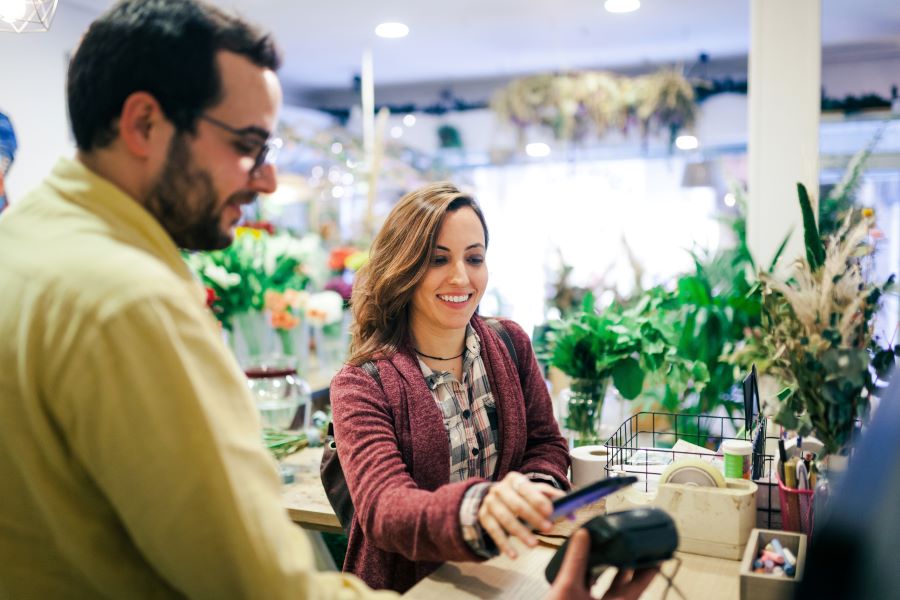 A young woman making a payment with a phone in the shop