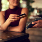 A woman pays with a credit card in a cafe.