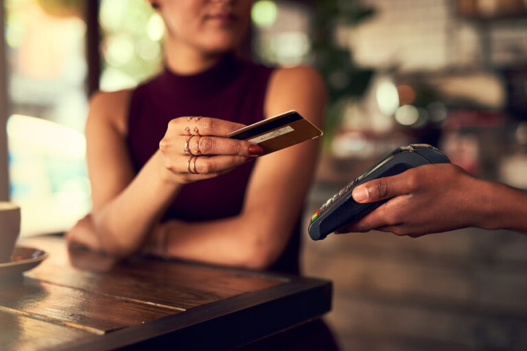 A woman pays with a credit card in a cafe.