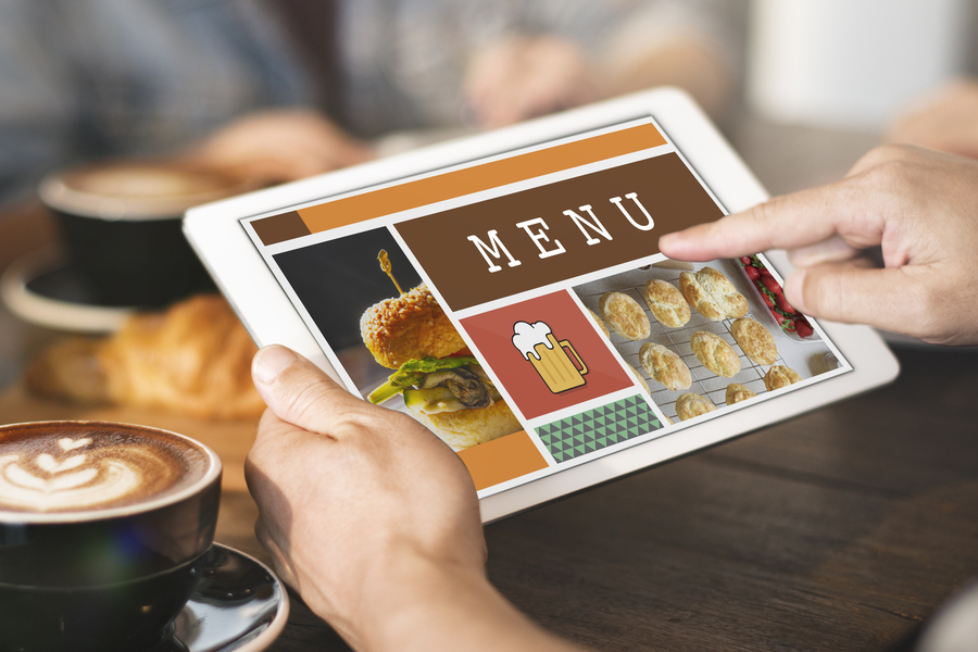 A customer in a cafe is choosing from a menu on a tablet. 