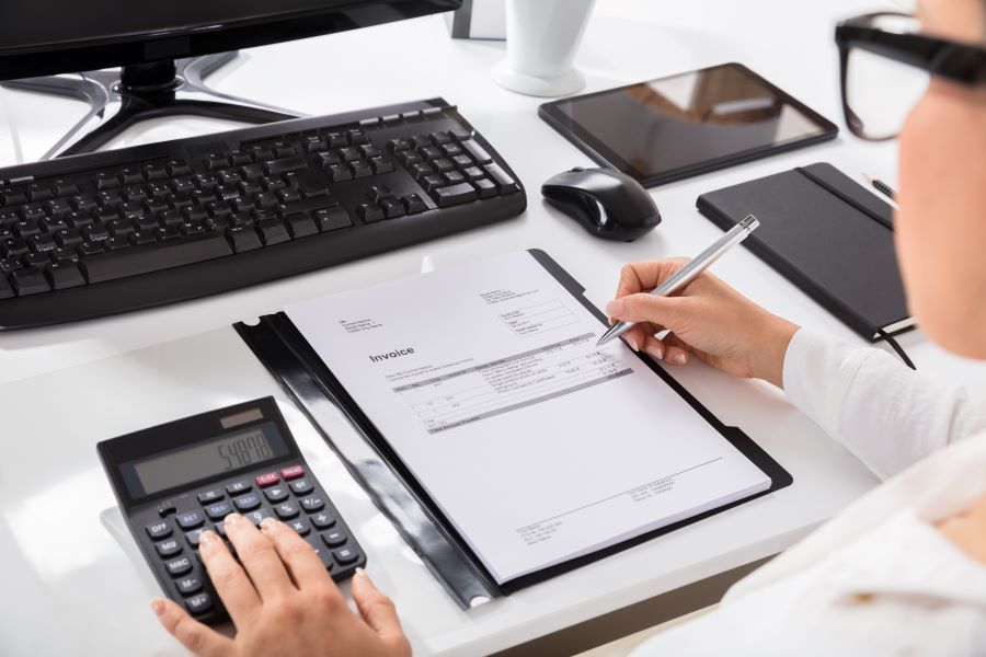 A businesswoman calculating a proforma invoice on her desk 