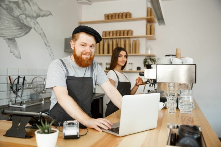 The cafe's owner working on a laptop at a modern coffee shop.