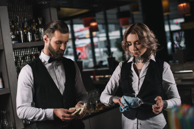 Bartenders counting tips in a bar.