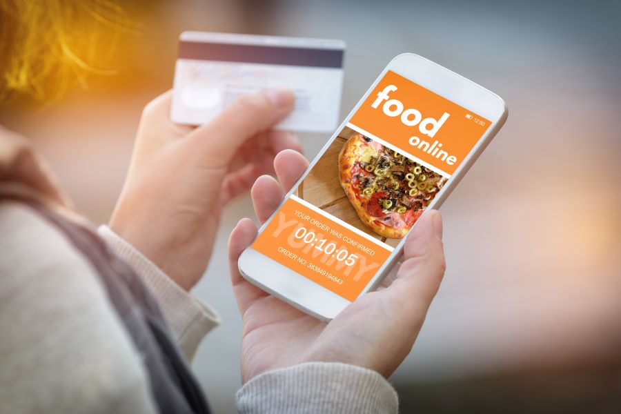 A woman holding a smartphone with a food online order on the screen. 