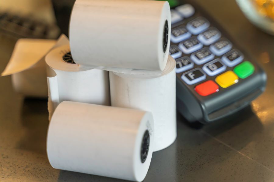 A bunch of receipt paper rolls and a card payment machine