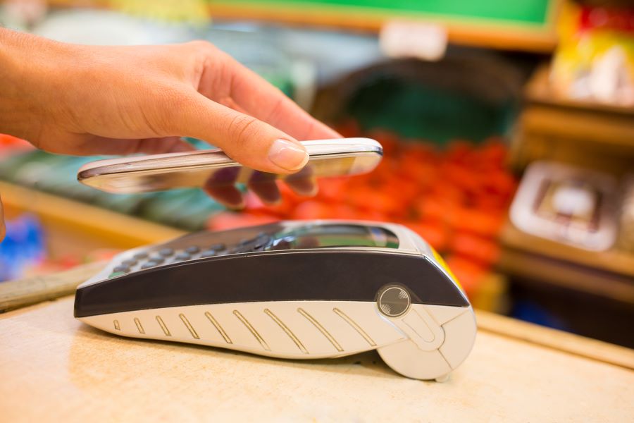 Woman paying with NFC technology on mobile phone, in supermarket 