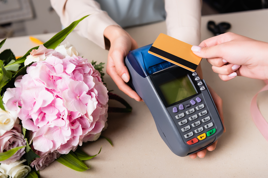 A customer paying on a card machine in a flower shop. 