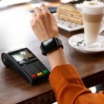 Woman making payment with smart watch in cafe