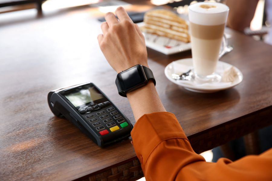 Woman making payment with smart watch in cafe