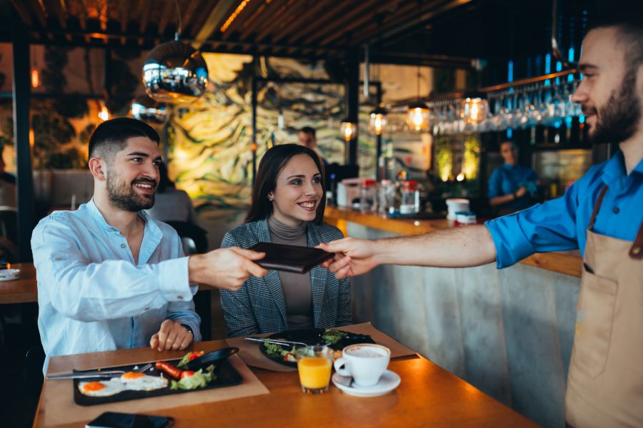 A happy couple giving a tip to the waiter in the restaurant