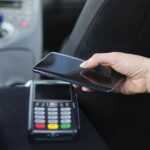 A customer paying in a London taxi contactless with a smartphone.