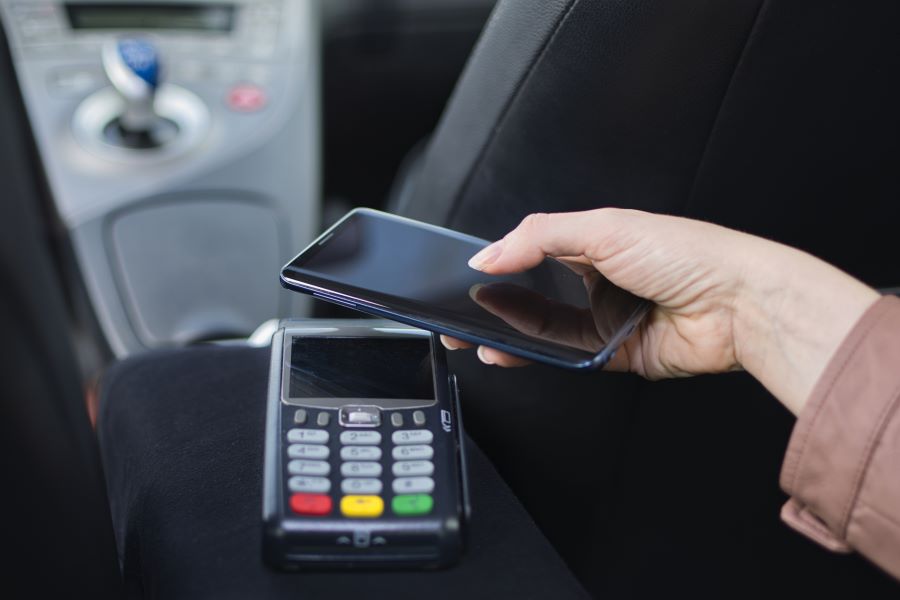 A customer paying in a London taxi contactless with a smartphone.