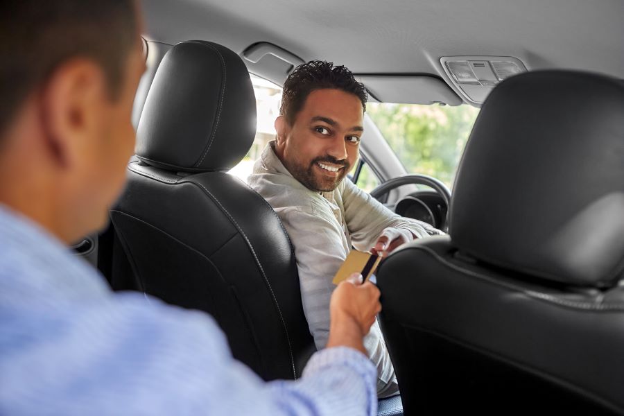 A taxi driver accepting credit card payments from a passenger. 