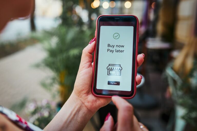 A woman holding a smartphone with Buy Now Pay Later on screen