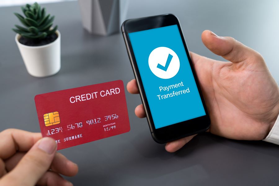 A businessman holding an iPhone with an iPhone Card Reader in hand.