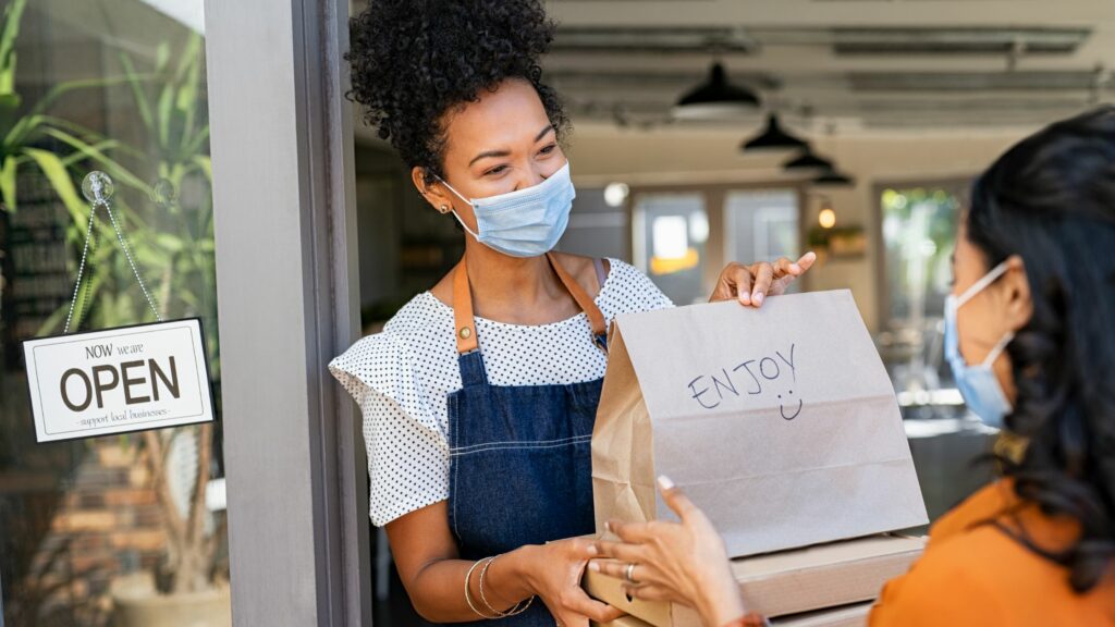 Woman Handing a Takeaway Bag to a Customer