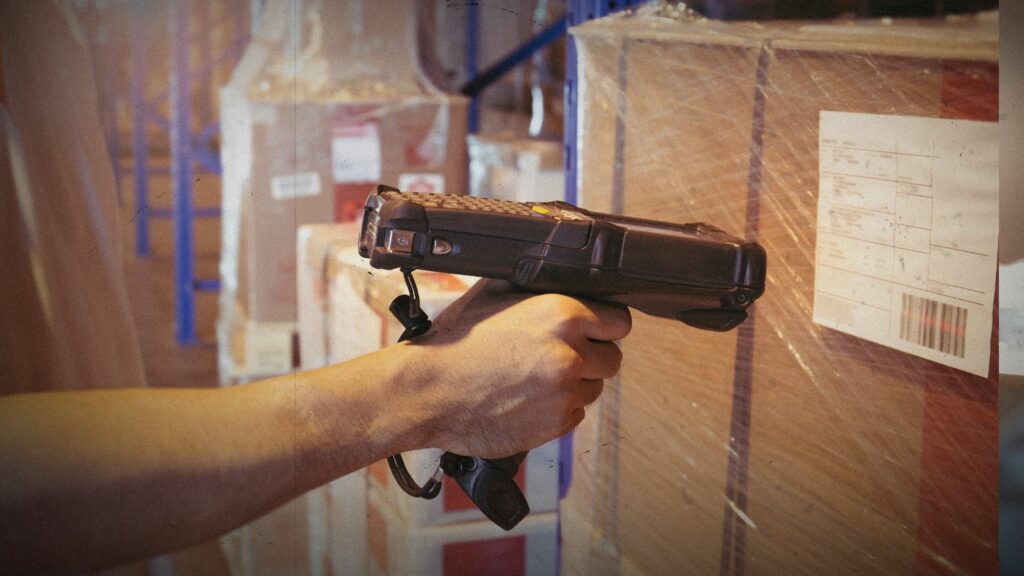 Worker scanning bar code scanner with label of goods. Computer equipment for warehouse inventory management.