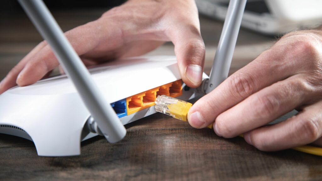 Man plugging internet cable into wifi router.